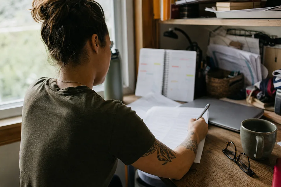 Over the shoulder view of a veteran filling in a printed medical questionnaire at a home desk
