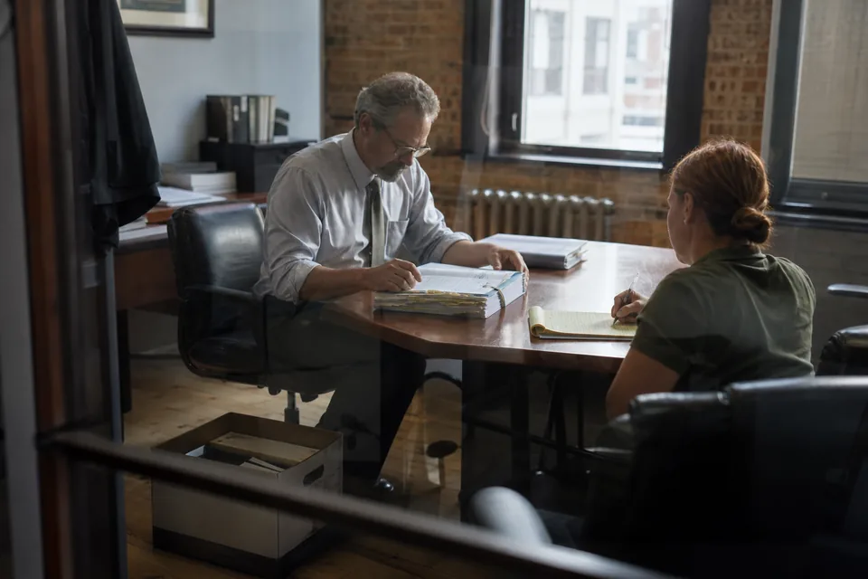 An attorney reviewing a thick case file with a veteran in a small law office meeting room