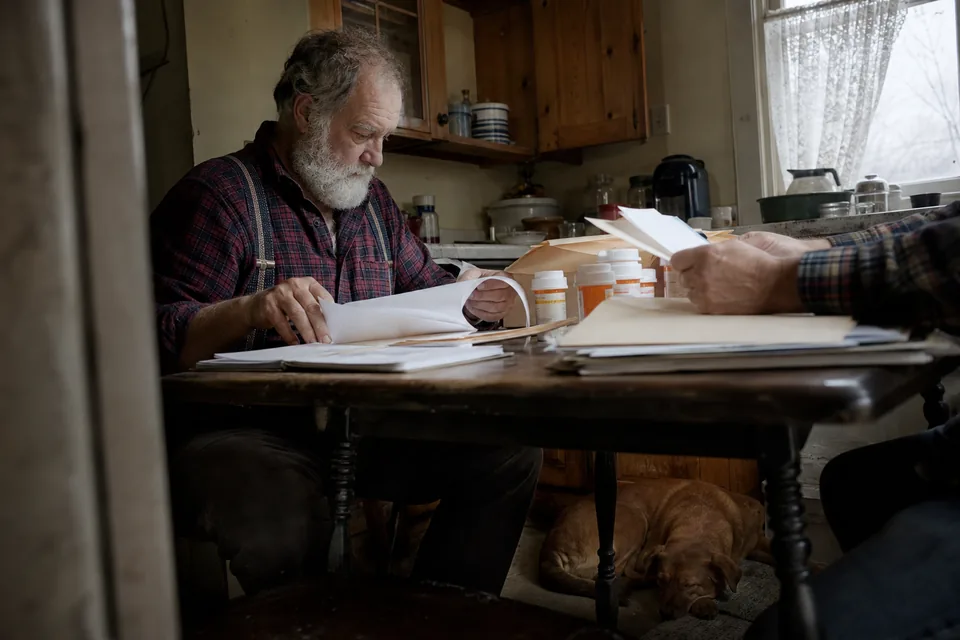 A veteran at a kitchen table sorting medical paperwork into folders before a first claim